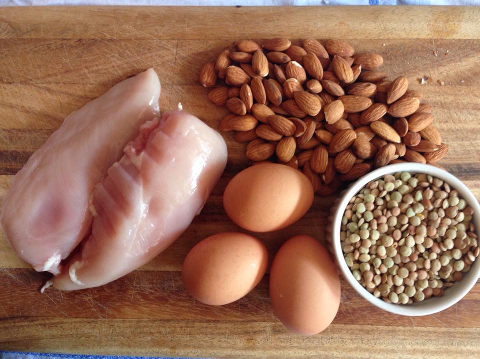 A spread of protein-rich foods including eggs, chicken, almonds, and lentils